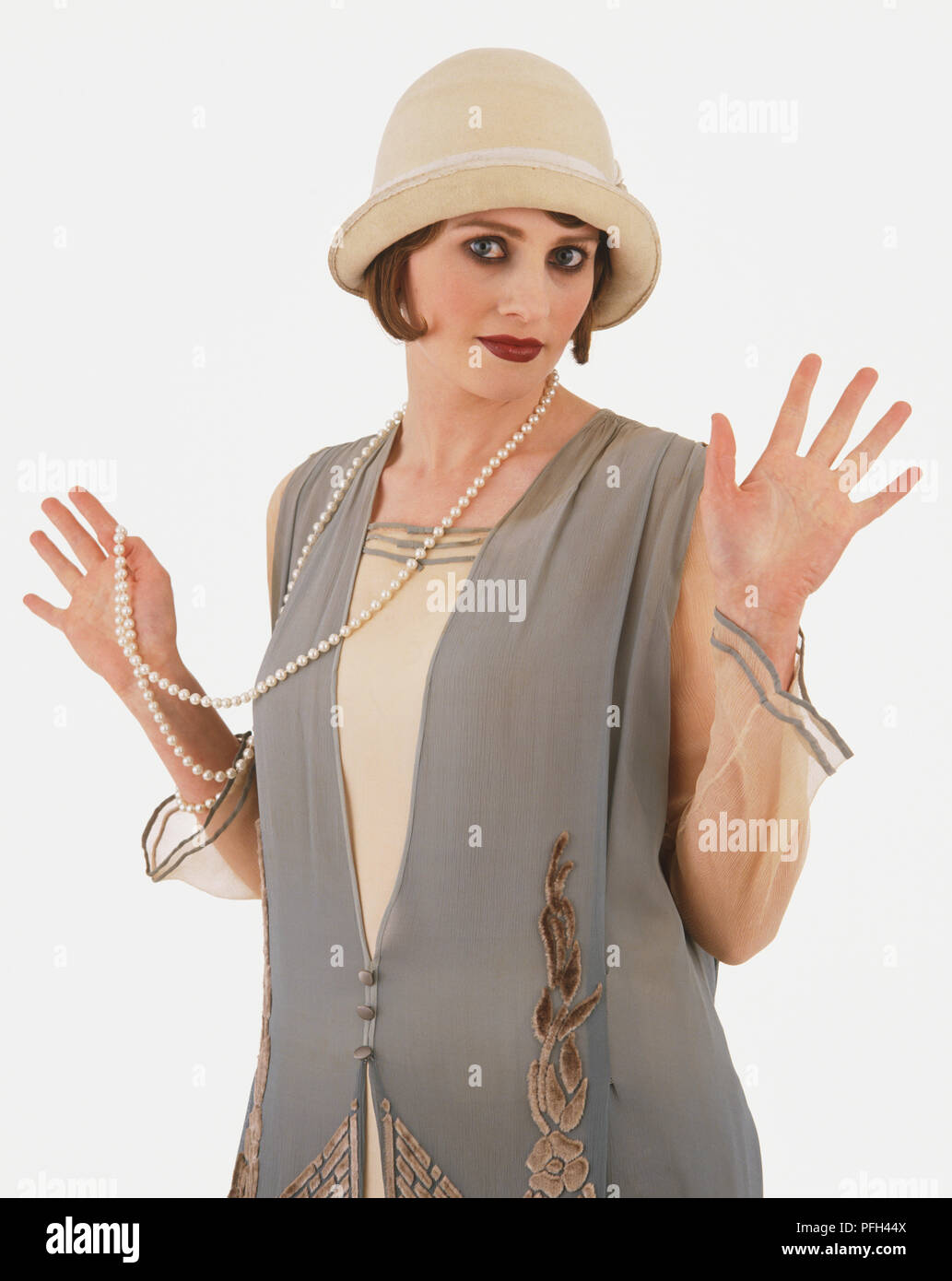 Donna che indossa 1920 abito e cappello, accolto " jazz " mani sollevando la sua collana di perle, guardando la fotocamera Foto Stock