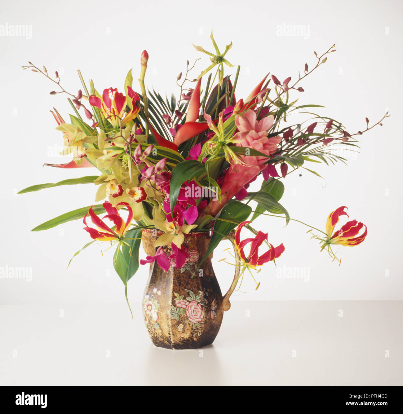 Rosso, rosa e giallo di fiori e foglie verdi disposti in un fiore-brocca di stampa Foto Stock