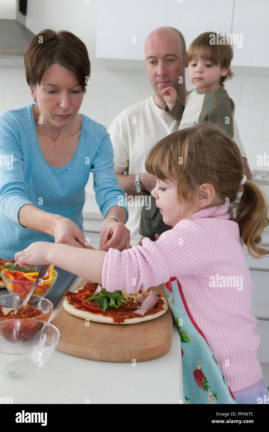 Uomo con ragazzo guarda la ragazza e la ragazza la preparazione di alimenti Foto Stock