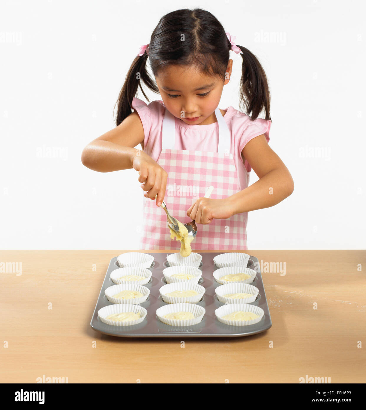 Ragazza spooning miscela in cupcake casi Foto Stock