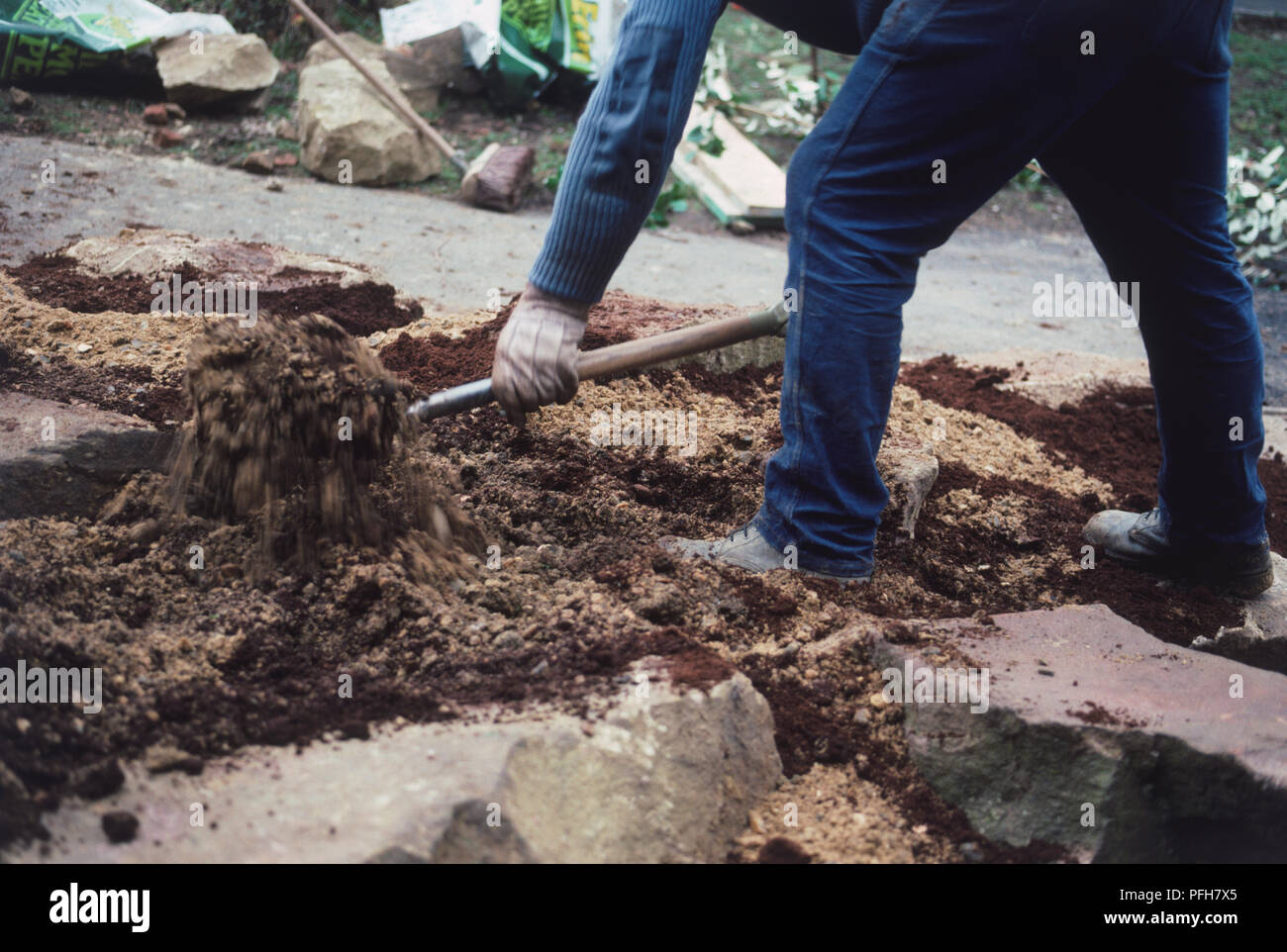 Giardiniere indossando i guanti e utilizzo di spade per preparare il suolo Foto Stock