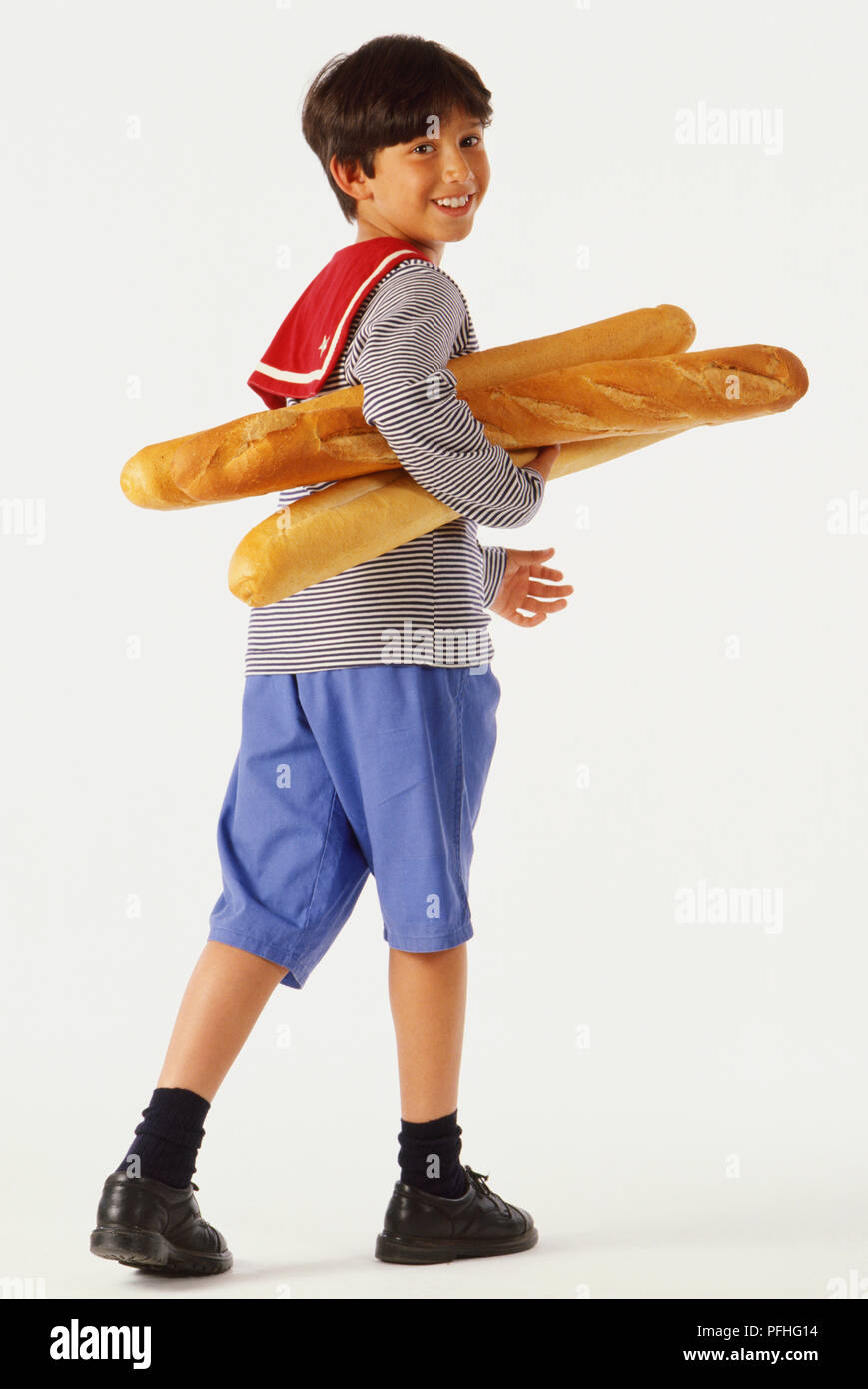 Ragazzo a piedi, indossando stereotipato abbigliamento francese e portando vari baguette sotto il braccio. Foto Stock