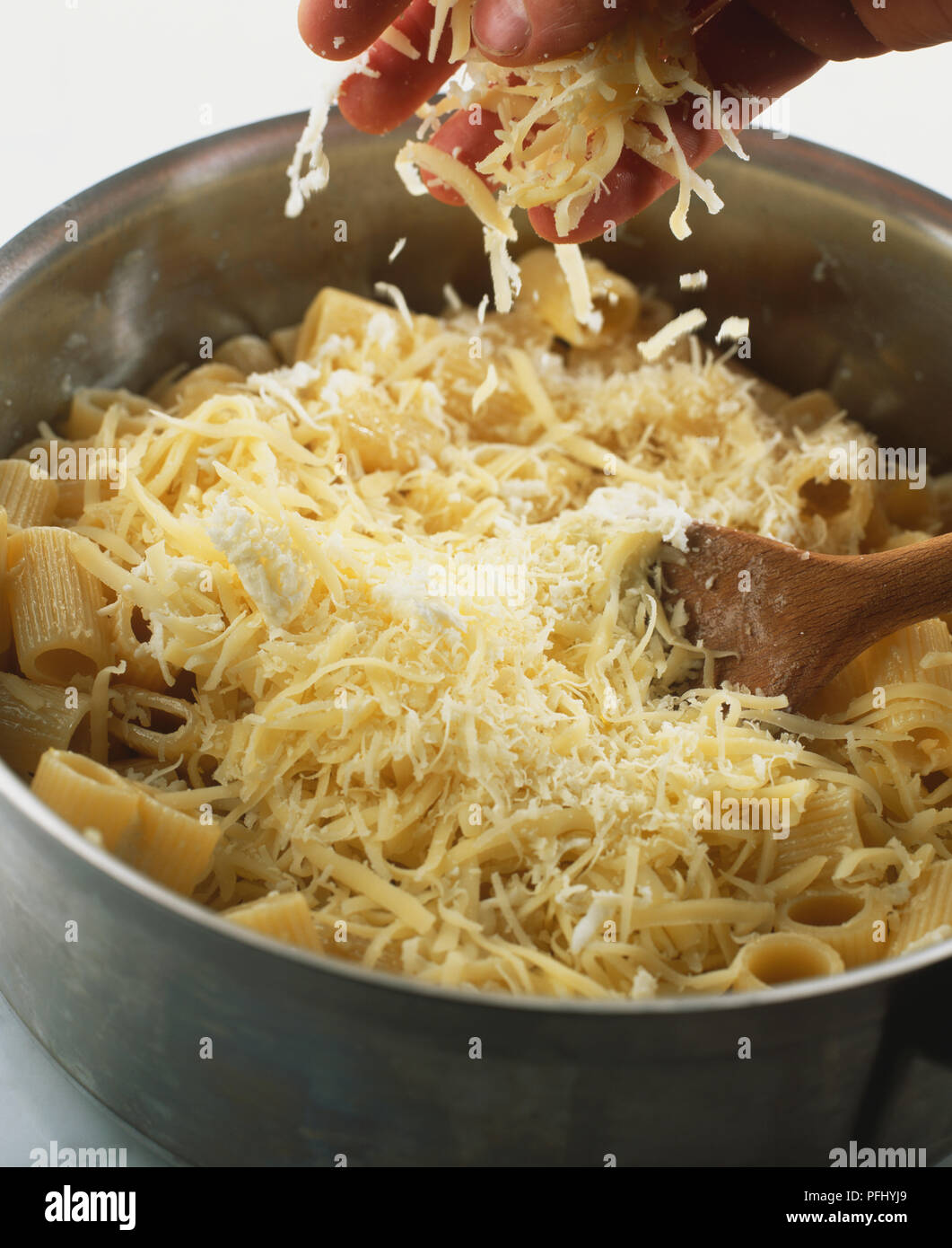 Parmigiano grattugiato essendo spruzzata sulla pasta in una pentola, vicino. Foto Stock