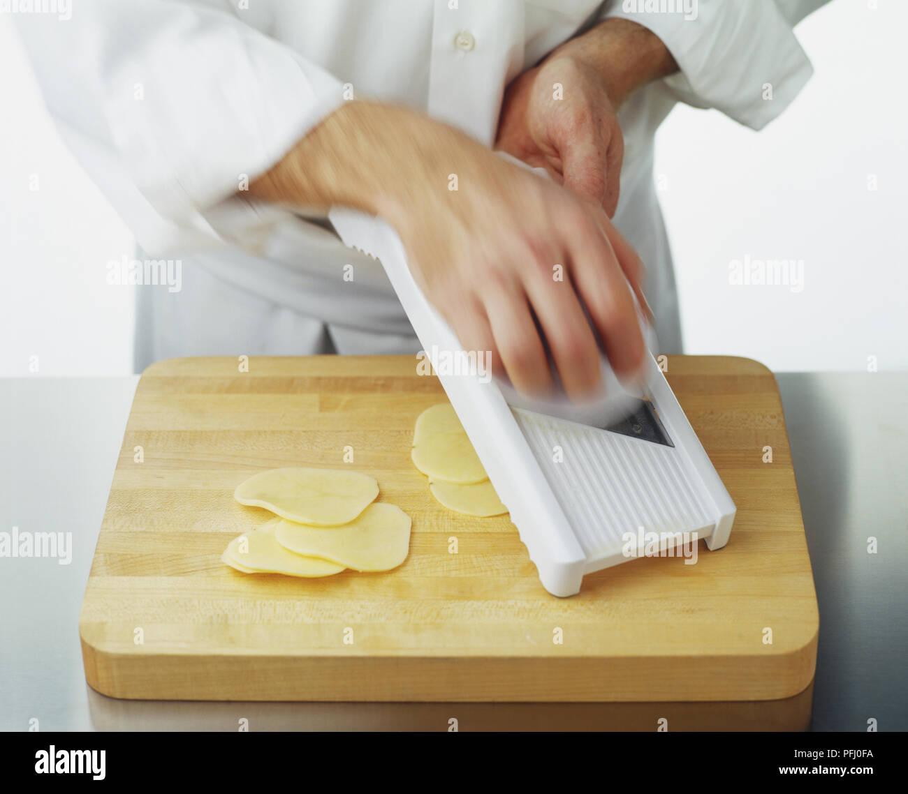 Utilizzando un mandolino per tagliare una patata a fettine sottili, movimento sfocato Foto Stock