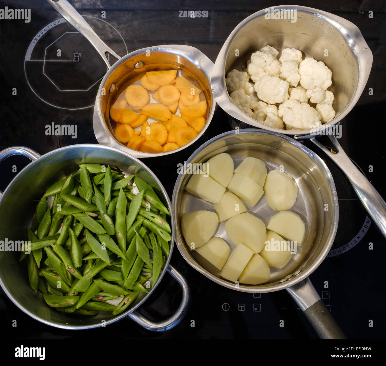 Quattro pentole in alluminio con verdure fresche sul piano di cottura ad  induzione in cucina domestica prima della cottura Foto stock - Alamy