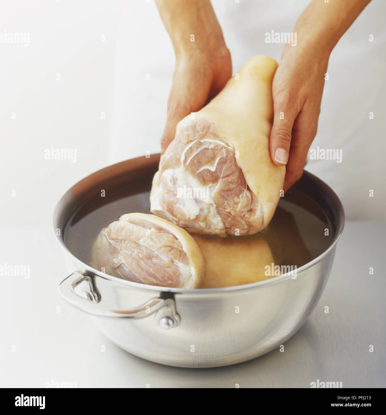 Mettere prosciutto garretti in una pentola riempita con acqua fredda Foto Stock