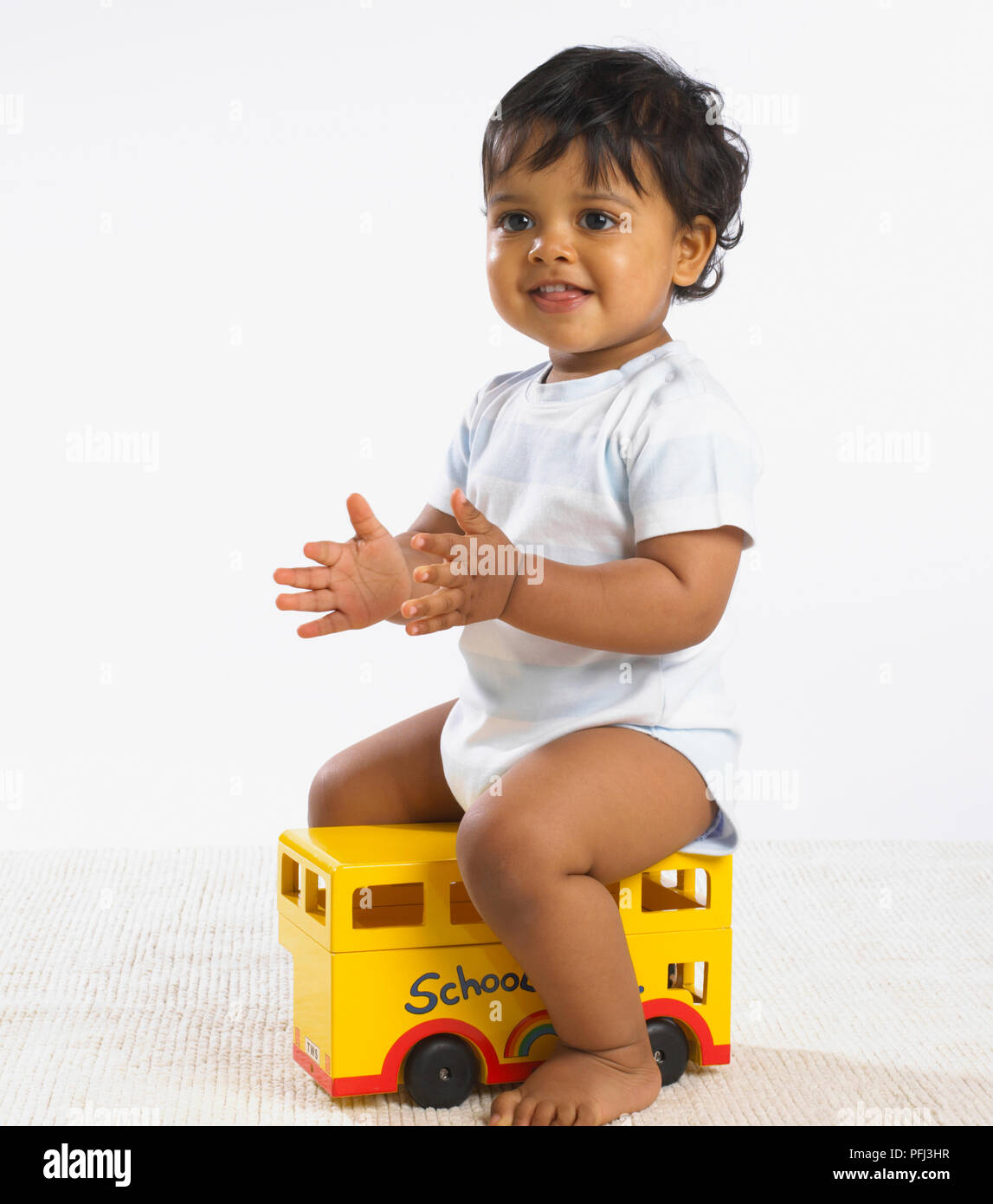 Baby ragazza seduta sulla parte superiore del bus giocattolo Foto Stock