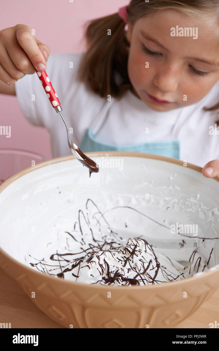 Ragazza con cucchiaio di salsa al cioccolato sopra la coppa Foto Stock
