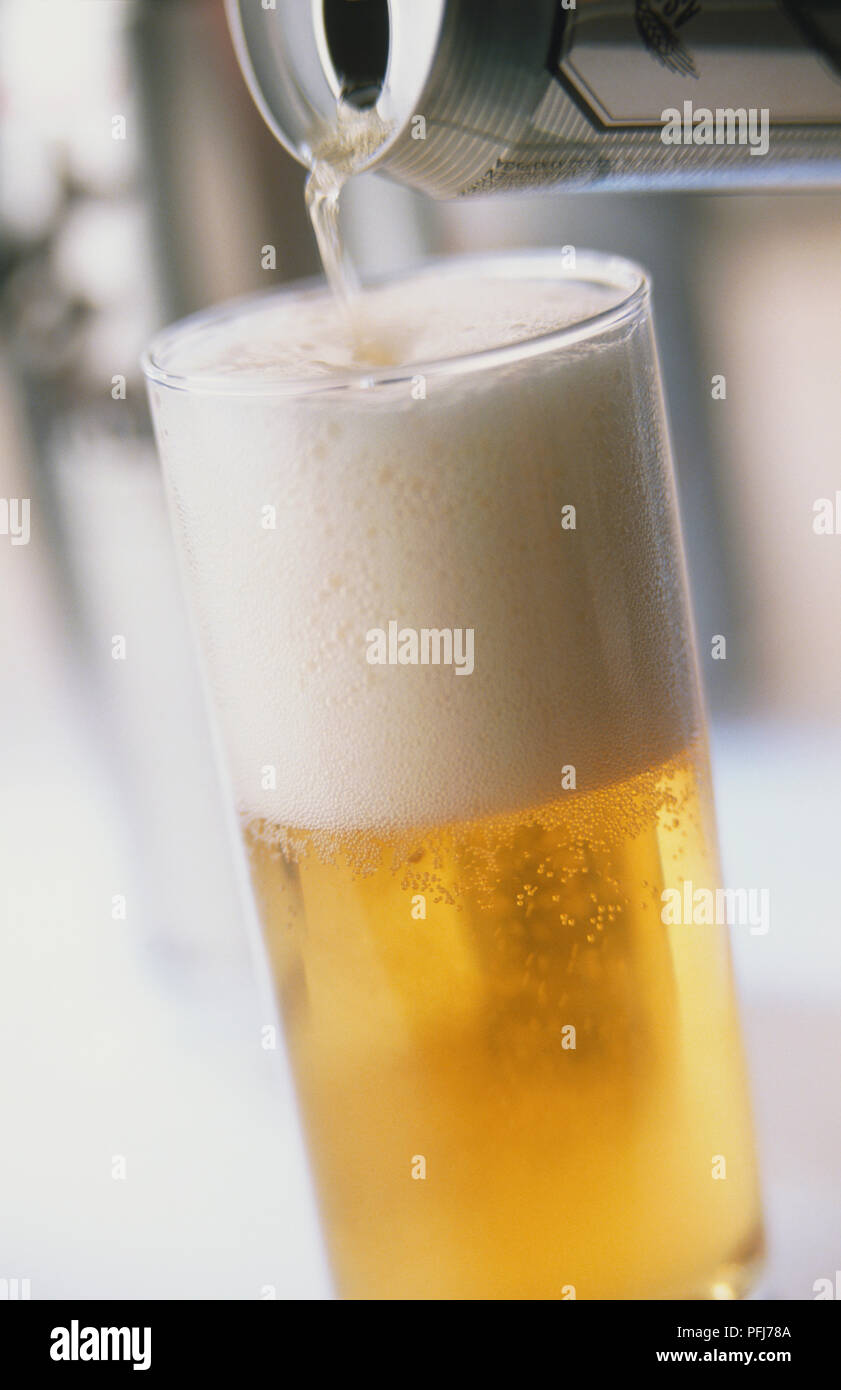 Birra che viene versata dal possibile in un bicchiere, vicino. Foto Stock