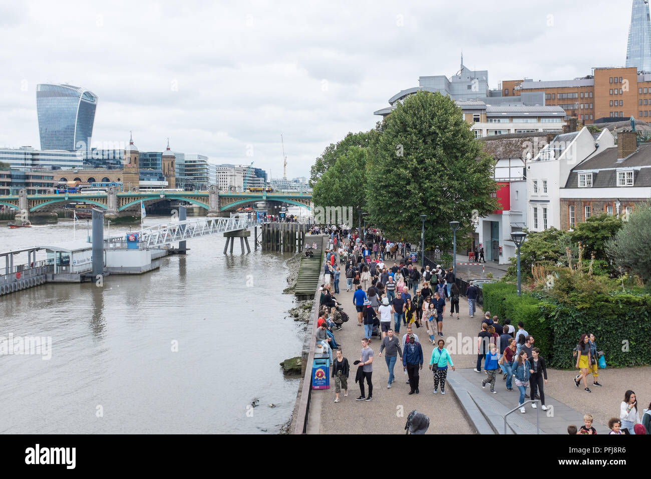 I turisti a piedi lungo il fiume Tamigi a Bankside vista dal Millennium Bridge di Londra Foto Stock