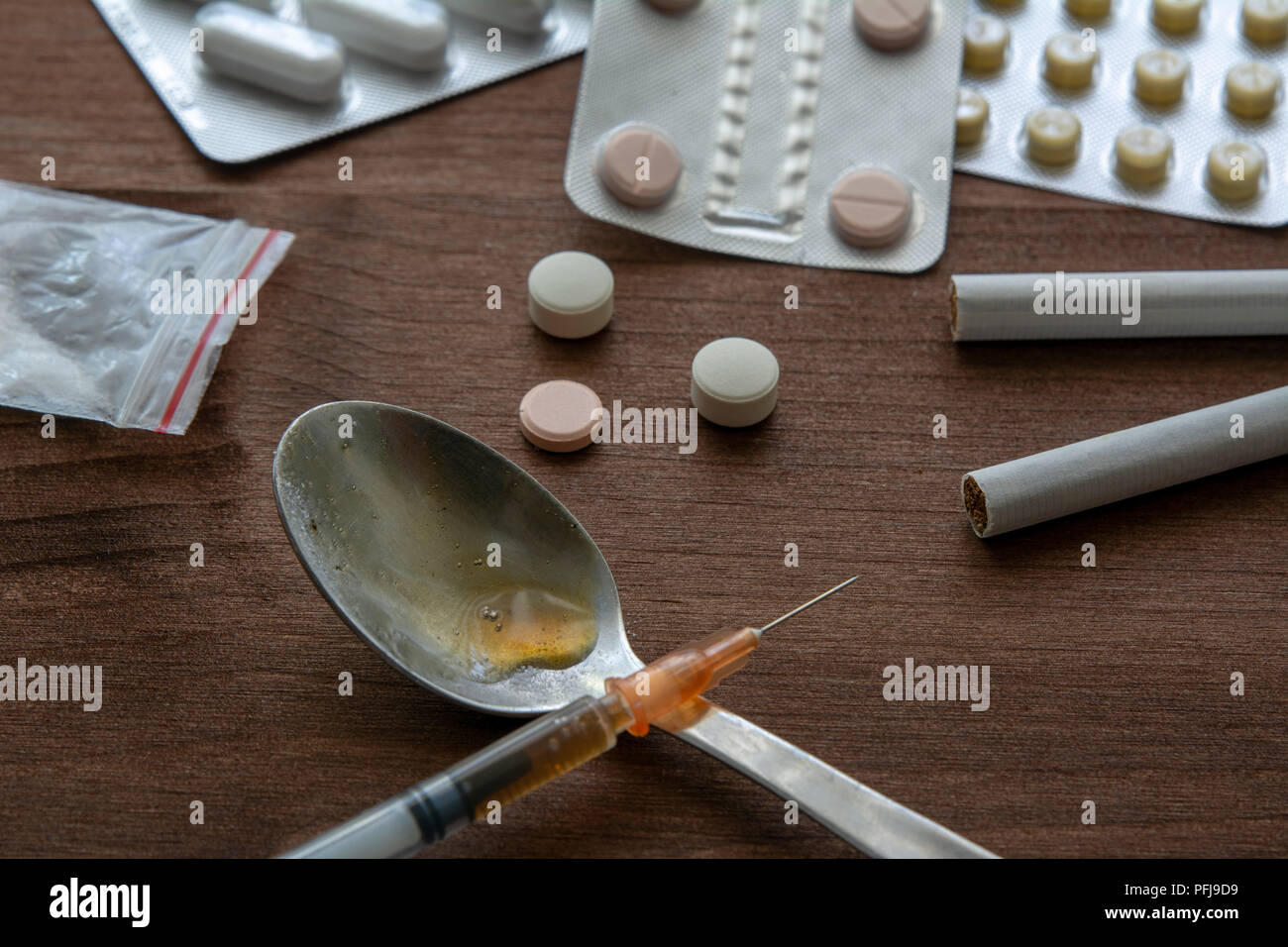 Siringa di farmaco e cotto eroina sul cucchiaio con le pillole di ecstasy e tabacco Foto Stock