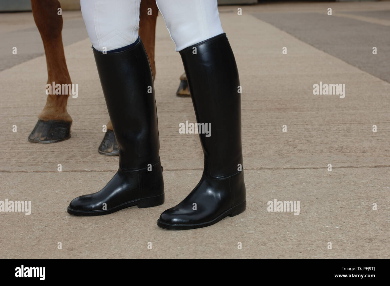 Le gambe di una donna vestita di nero stivali da cavallo, a cavallo per le  gambe in background, close-up Foto stock - Alamy