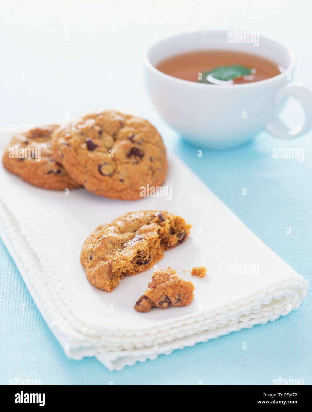 I cookie su un piegato tovagliolo bianco e un bicchiere di raccordo a t a base di erbe Foto Stock
