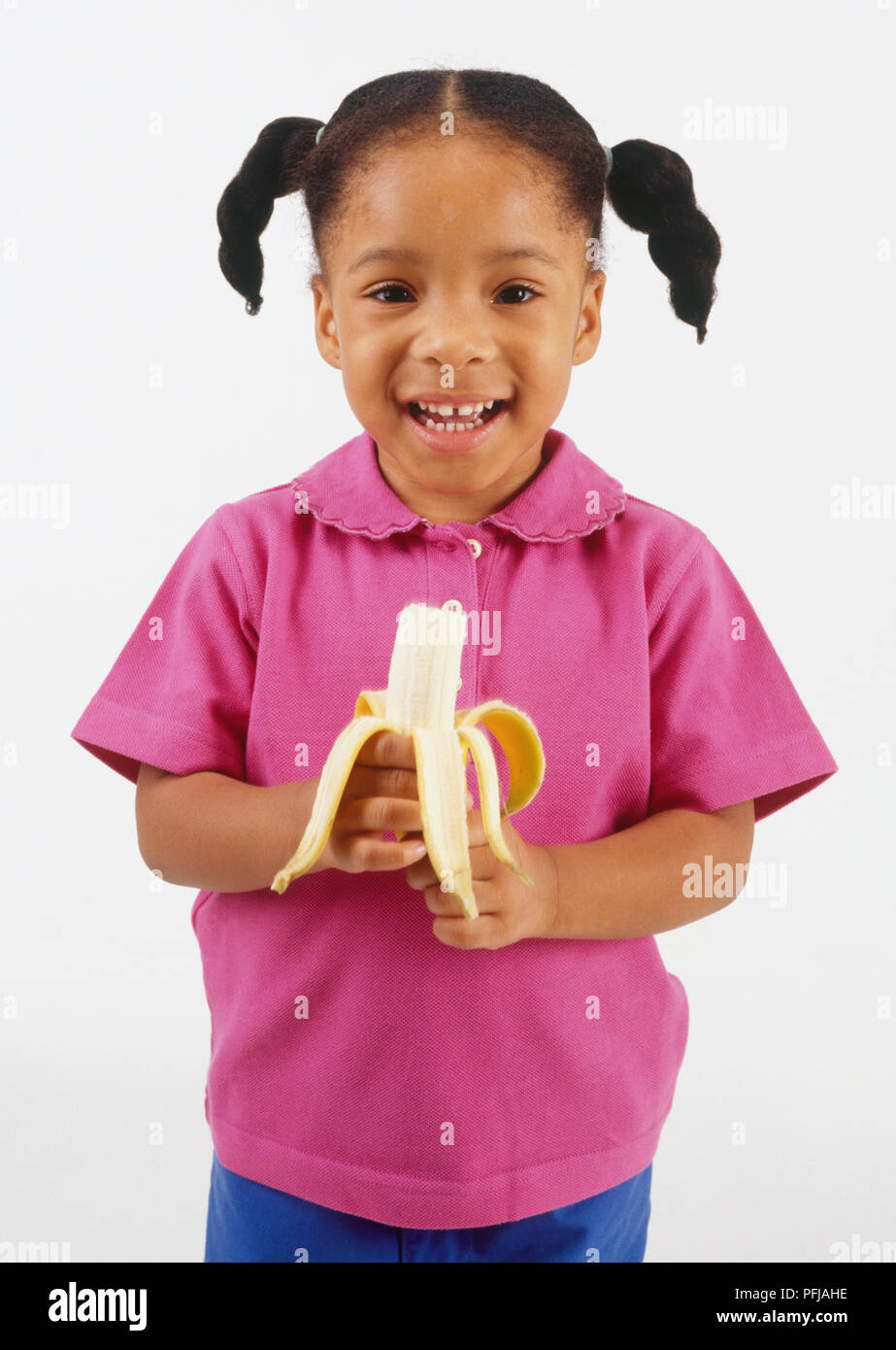 Ragazza in maglia rosa tenendo una banana, vista frontale Foto Stock