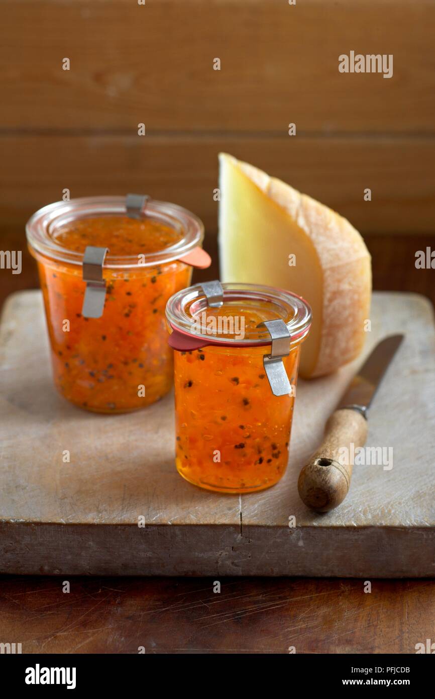 Carota e cardamomo marmellata accanto al formaggio e il coltello sul tagliere, close-up Foto Stock