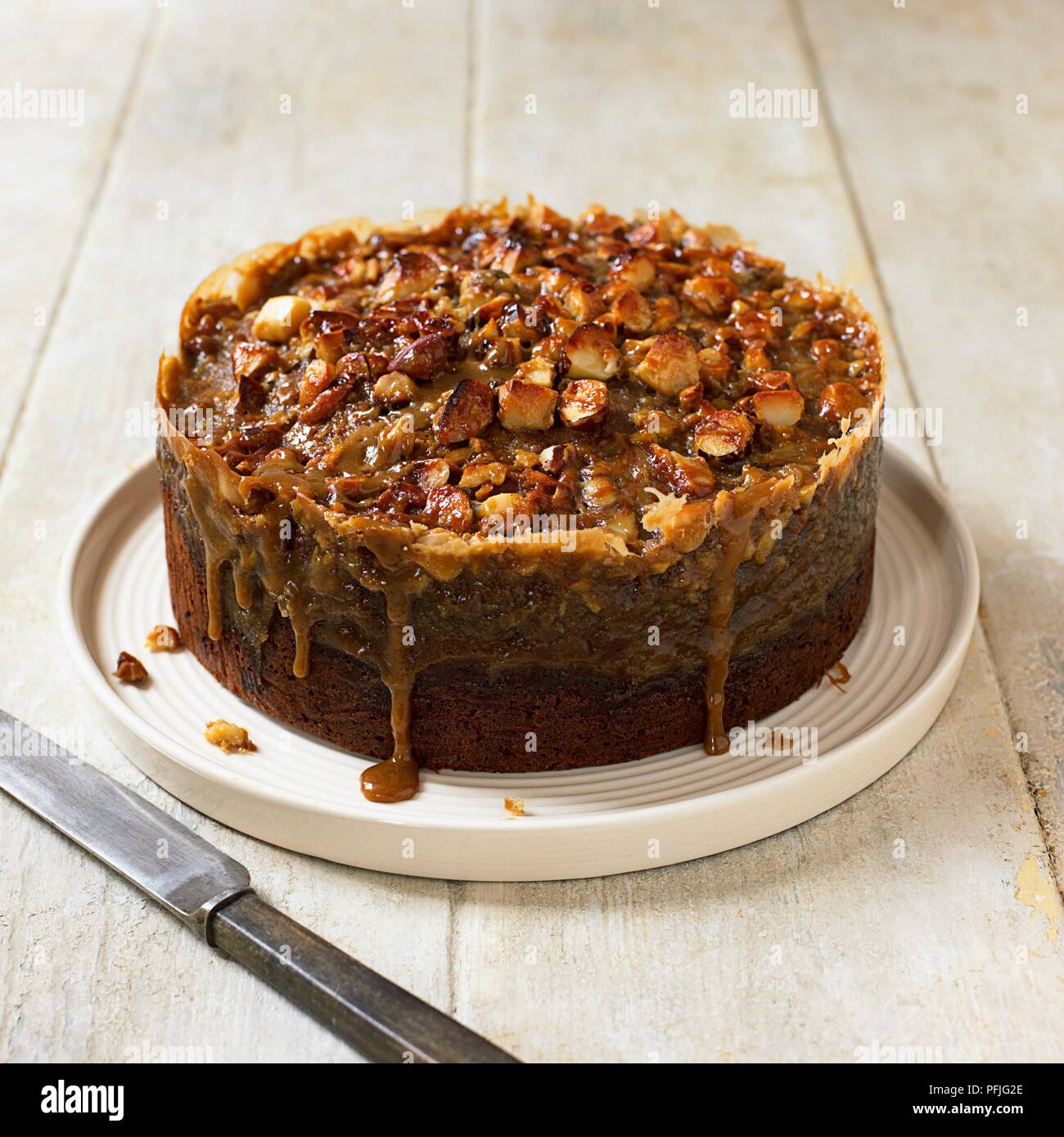 Toffee Banana torta guarnita con i dadi, coltello nelle vicinanze Foto Stock