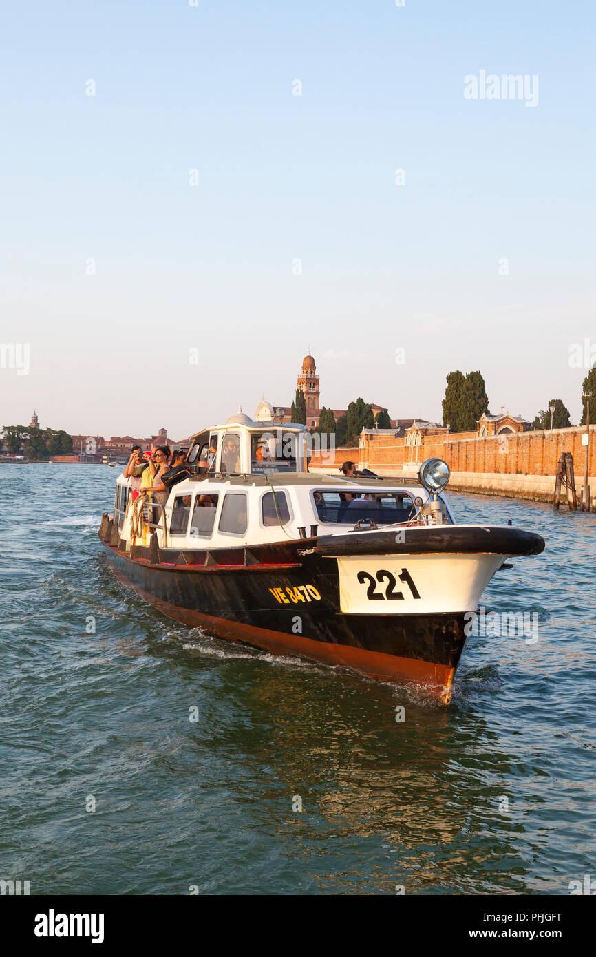 Vicino la vista frontale di un vaporetto vaporetto, acqua bus, Venezia, Veneto, Italia attraversando San Michele isola al tramonto pieno di gente turisti. Tra pubblico Foto Stock