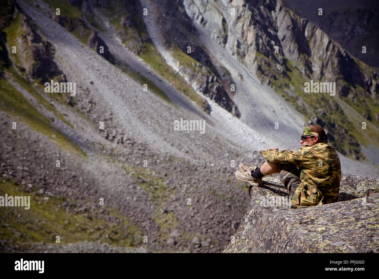 Giovane uomo si siede su una pietra a guardare il panorama delle montagne di Altai in Russia Foto Stock