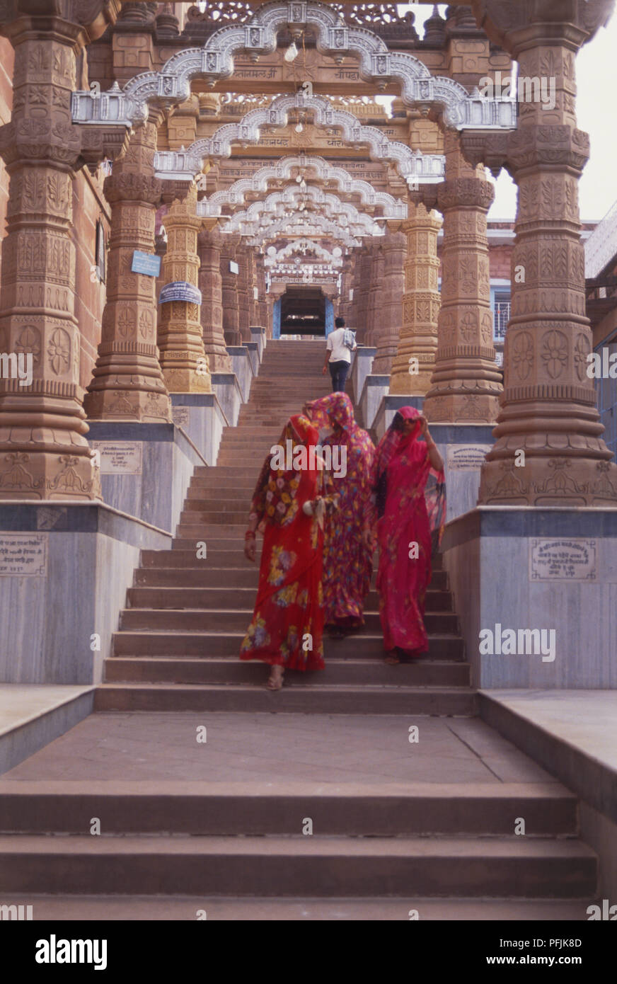 India Rajasthan, Osian, Sachiya Mata Temple, donne in variopinti abiti tradizionali a piedi fino a montante di gradini rivestiti che conduce al tempio ingresso, vista posteriore. Foto Stock