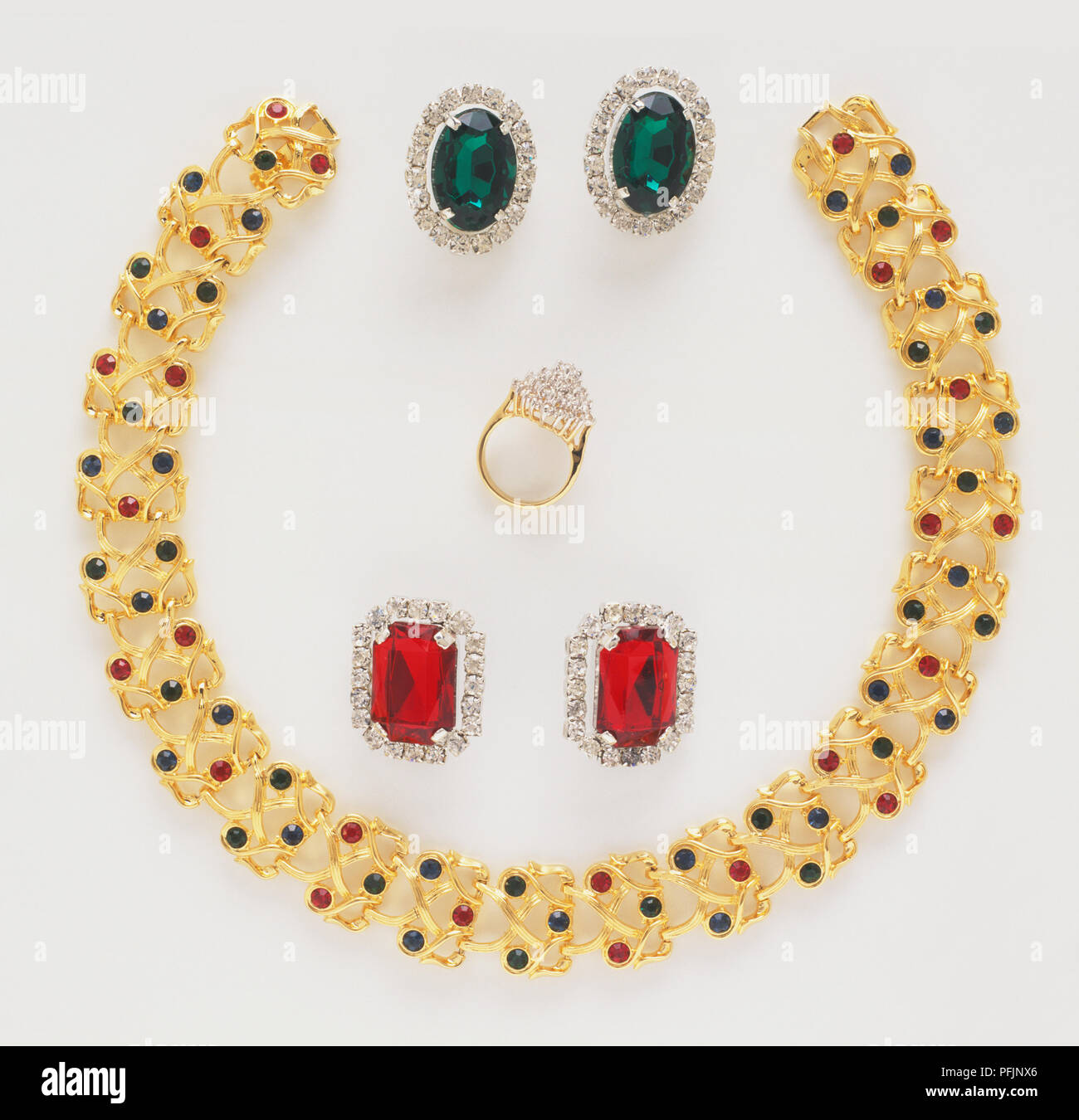 Collana in oro con il rosso e il verde dei gioielli, corona diamantata e coppie di rosso rubino e gemma verde orecchini Foto Stock