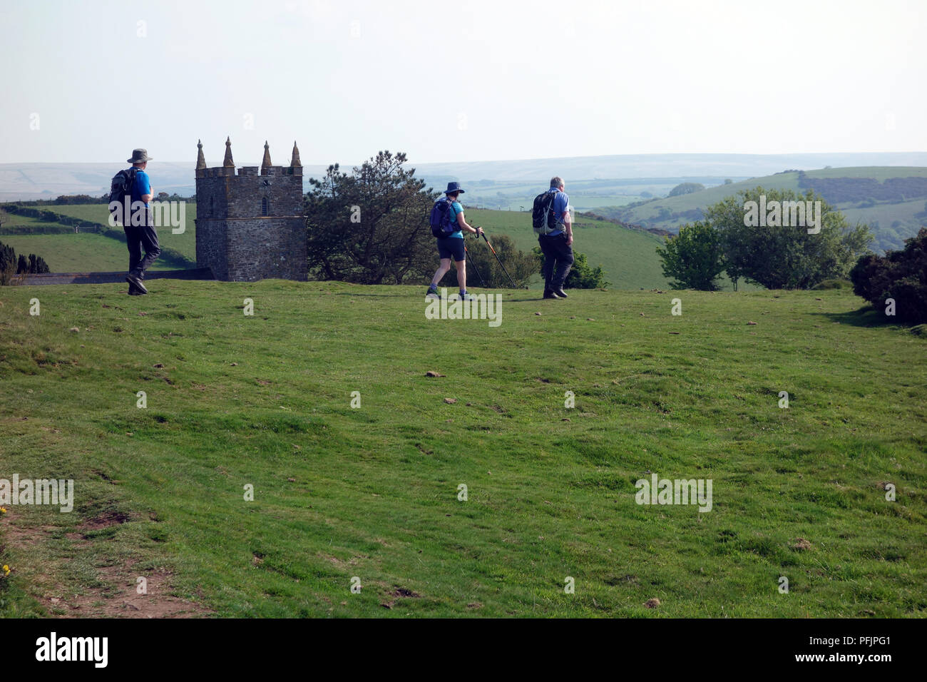 Tre gli escursionisti a piedi passato San Giovanni Battista in Countisbury sul sud-ovest sentiero costiero, Devon, Inghilterra, Regno Unito. Foto Stock