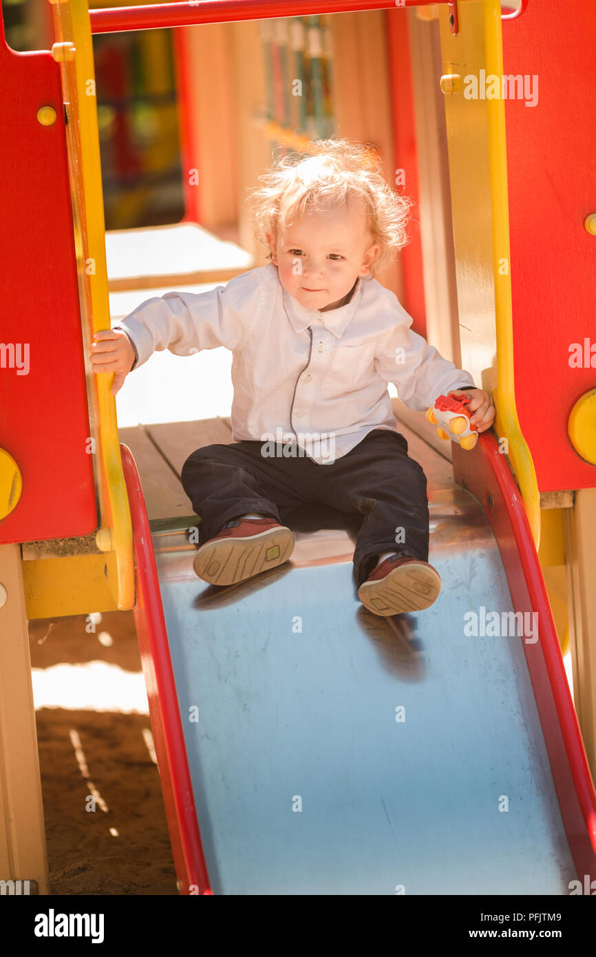 Carino baby boy giocando su una slitta sul parco giochi Foto Stock