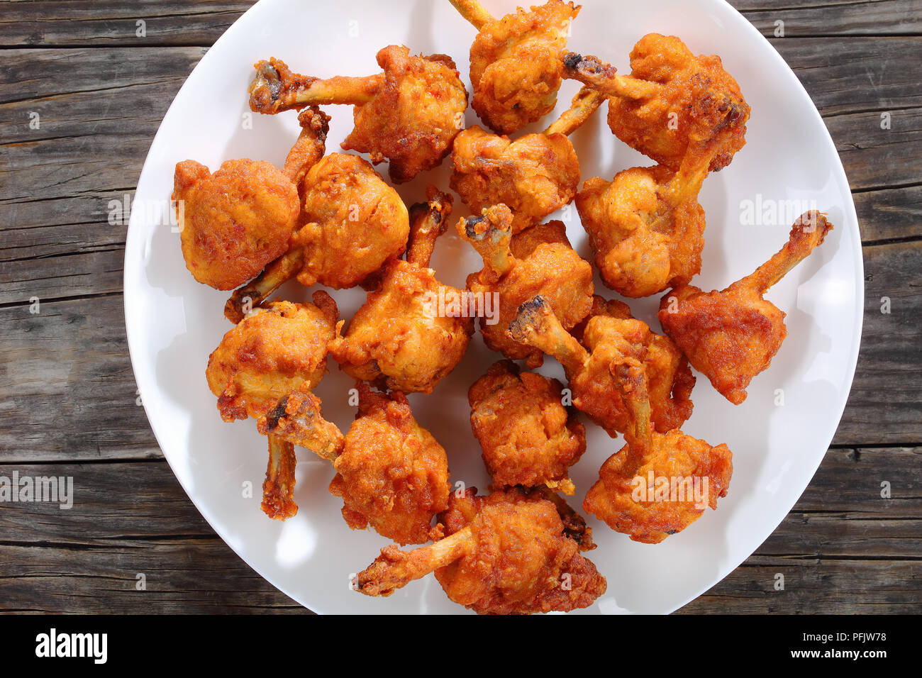 Deliziosi fritti martoriata pollo croccante alette di estremità su una piastra bianca sul legno scuro tabella, vista orizzontale dal di sopra Foto Stock