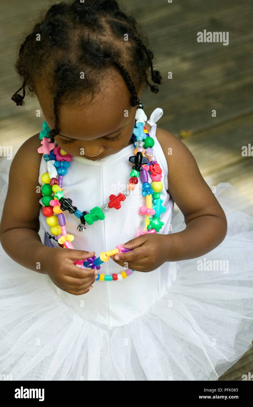 Bambina indossa tutu bianchi e colorati collane di plastica, close-up Foto Stock