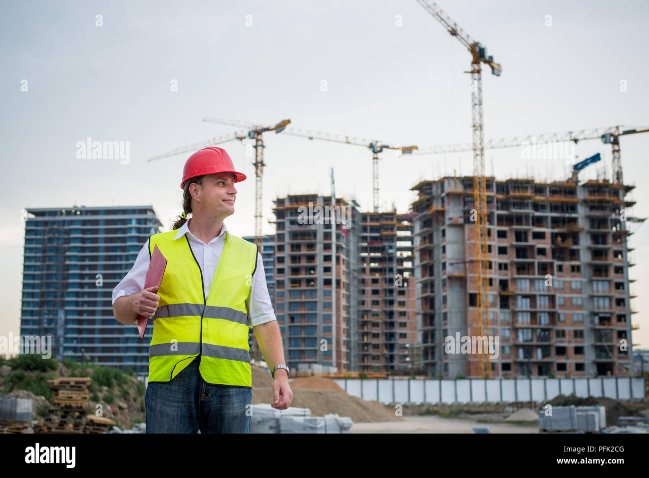 Caposquadra su un cantiere indossano ovest riflettente lavorando sul progetto di alloggiamento Foto Stock