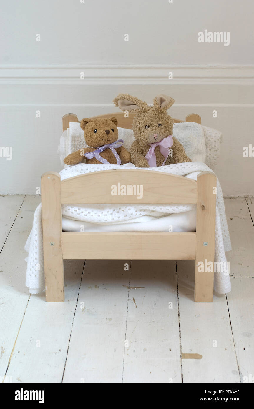 Coniglio giocattolo e orsacchiotto sat in giocattolo letto in legno Foto Stock