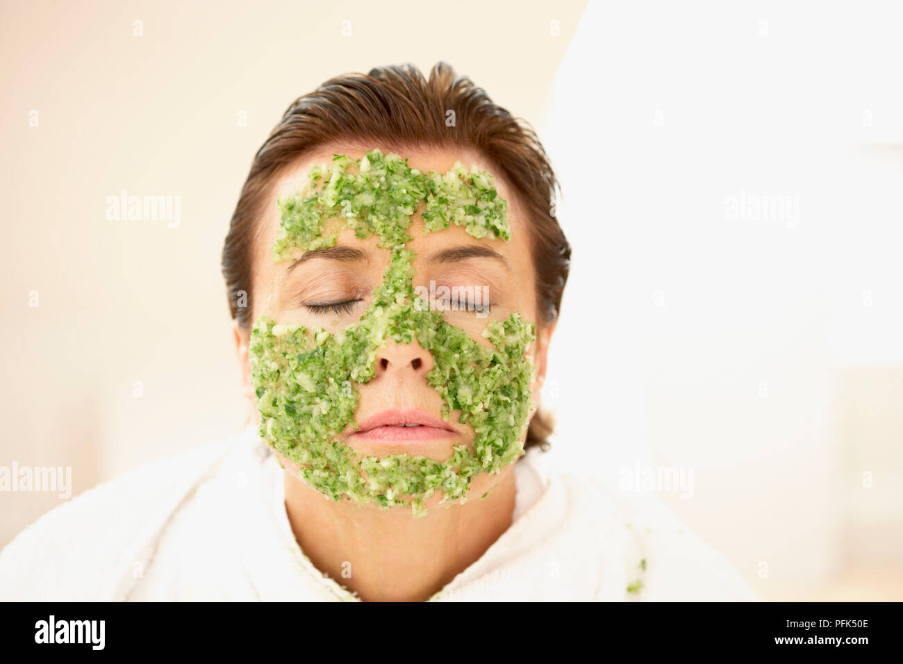 Donna in accappatoio in spugna, chiudere gli occhi, indossa la maschera per il viso, testa e spalle Foto Stock