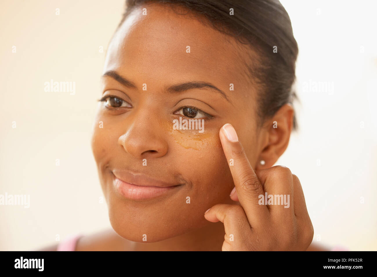 Donna applicazione di olio al sotto la zona degli occhi con la punta delle dita Foto Stock