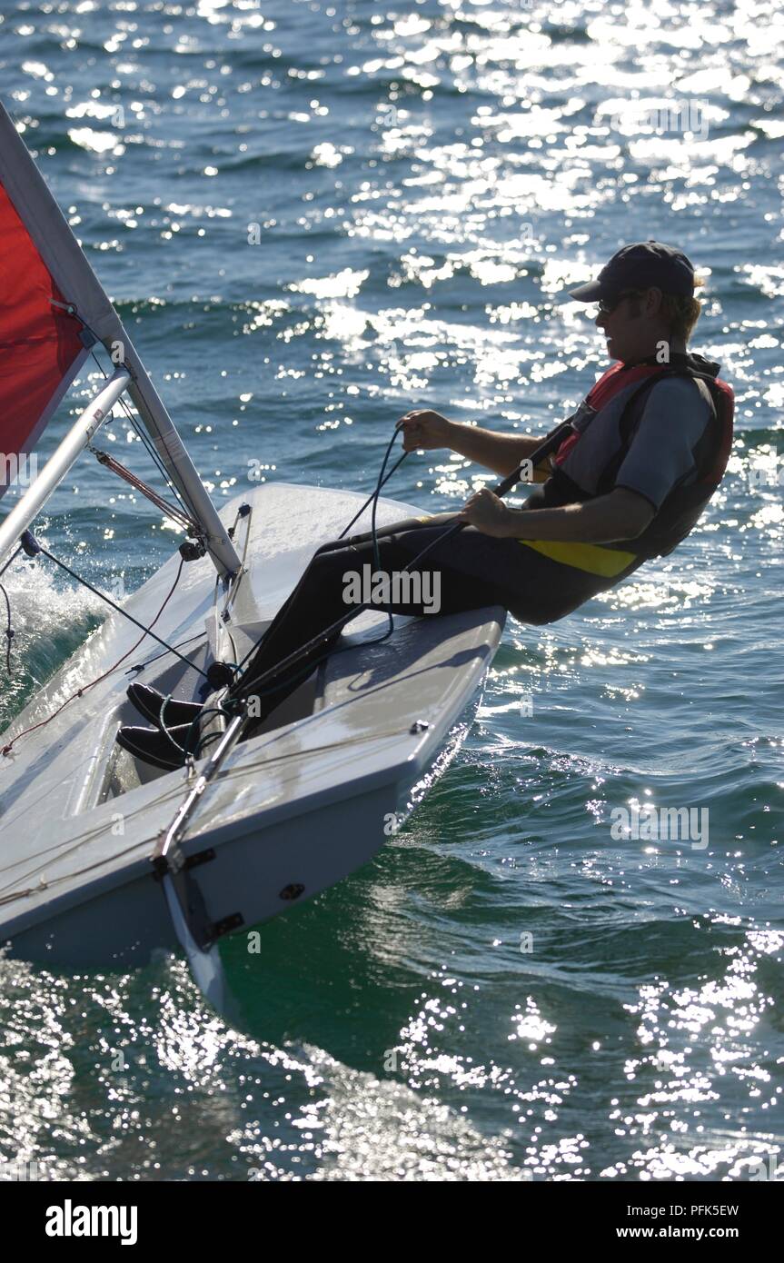 La Turchia, giovane uomo che indossa il giubbotto di salvataggio vela laser classe dinghy, appoggiata al di fuori del lato di dritta Foto Stock