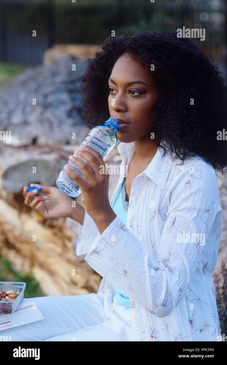 Donna che mantiene una bottiglia di acqua per la sua bocca Foto Stock
