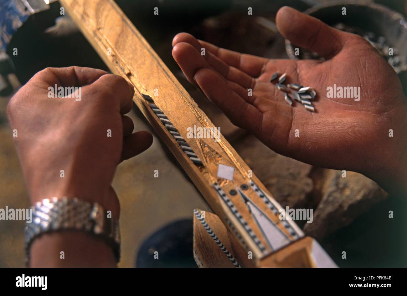 Cina, Xinjiang, Kashgar, mani rendendo tradizionale strumento musicale 'duttar', decorare con intarsio in bianco e nero di pezzi Foto Stock