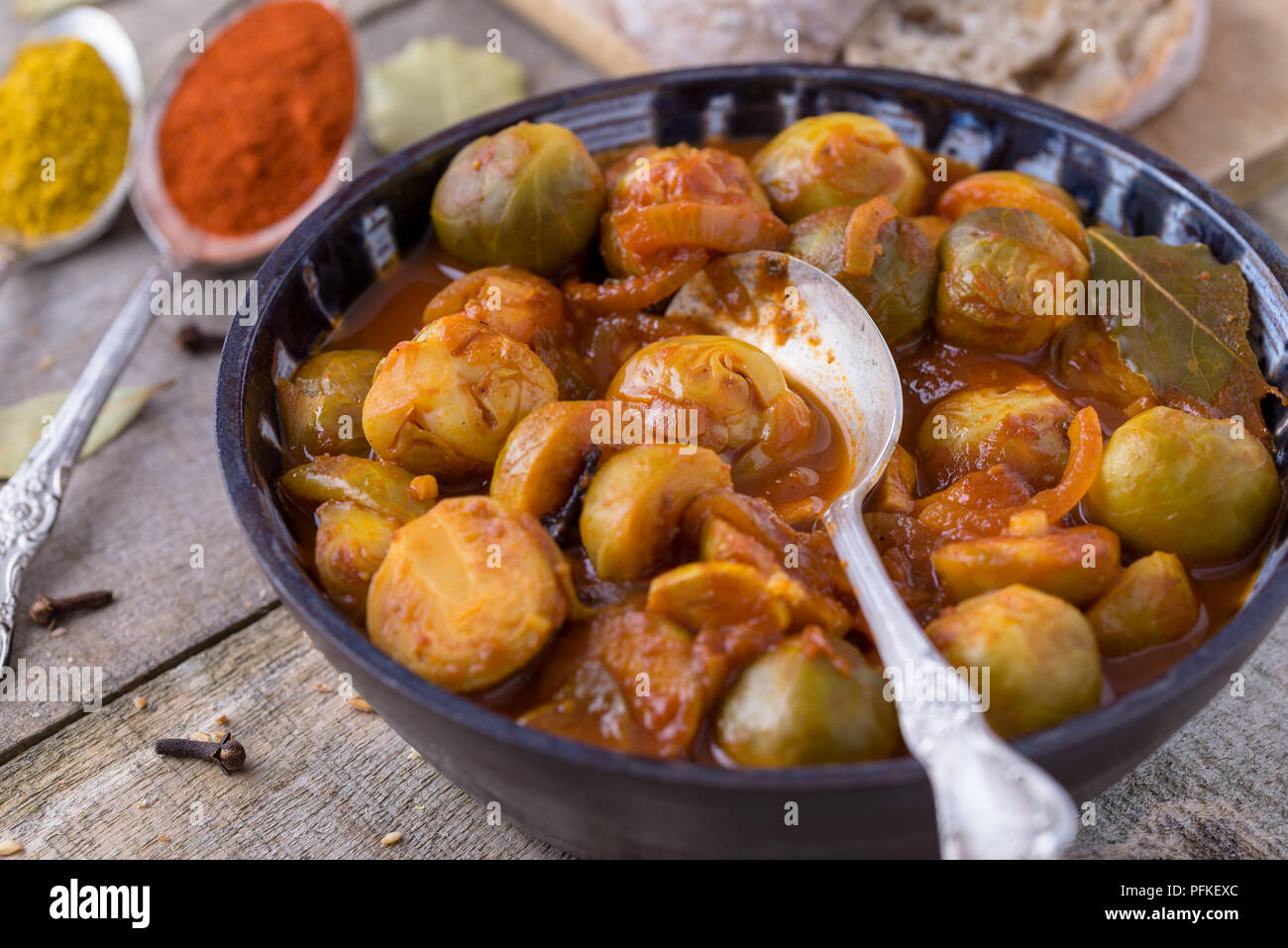 Arrosto di cavolini di Bruxelles la zuppa in ceramica artigianale ciotola di legno naturale dello sfondo. Foto Stock