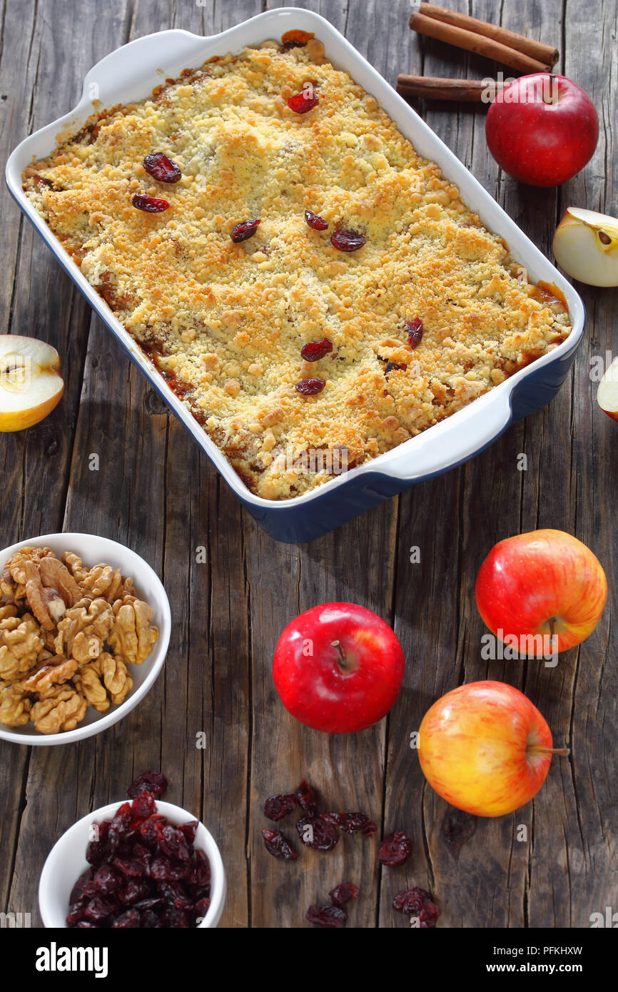 Deliziosa apple crumble o apple crisp in una teglia con ingredienti sul legno scuro tabella, vista verticale da sopra Foto Stock