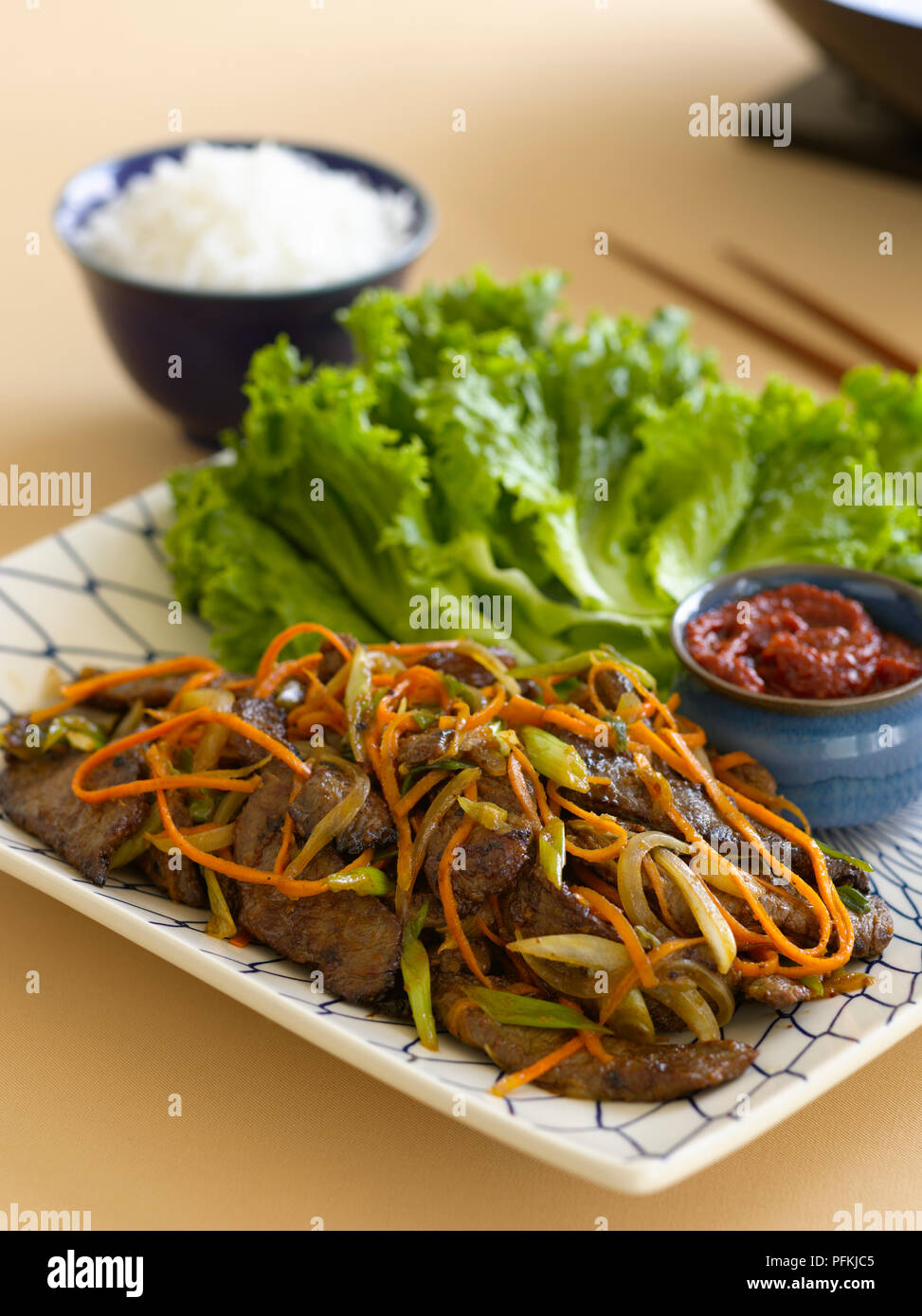 Bulgosi ssambap, coreano lattuga wrap fatto con carne di manzo e strisce di cipolla e carota, servita come ingredienti separati su una piastra con il piccante pasta di fagioli e una ciotola di riso Foto Stock