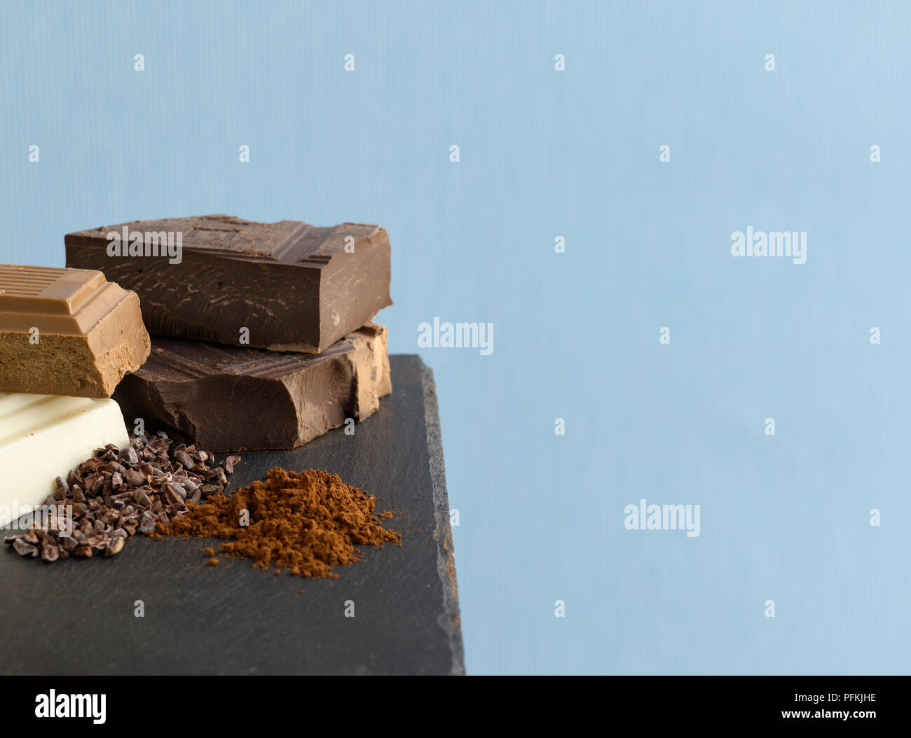 Blocchi di cioccolato bianco, cioccolato al latte e cioccolato fondente, frantumato le fave di cacao e polvere di cacao Foto Stock
