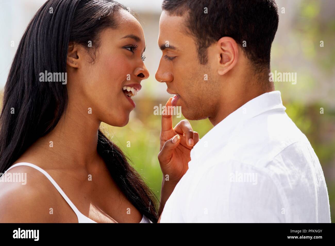Uomo che guarda in occhi di donna come essi abbracciano come lei tocca il suo labbro con il suo dito indice Foto Stock