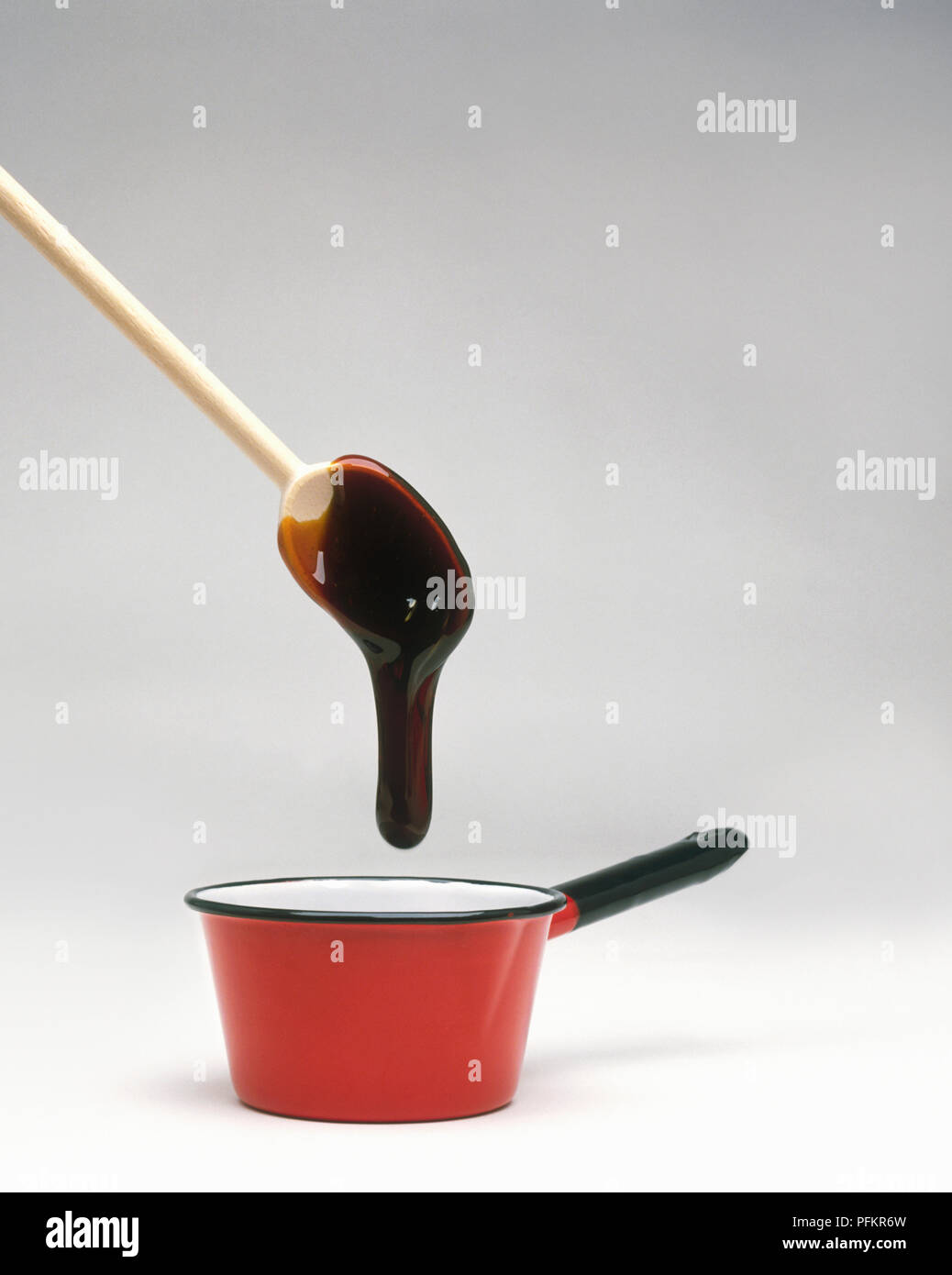 Toffee gocciolamenti dal cucchiaio di legno nella pentola Foto Stock