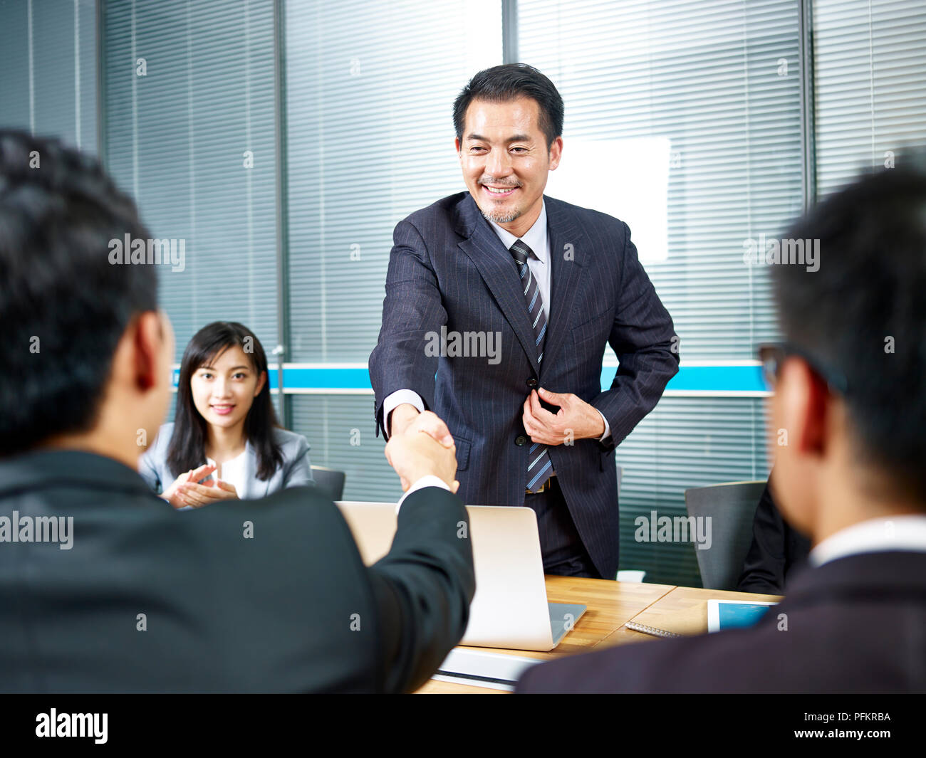 Due asian business uomini stringono le mani su tavolo riunione prima di negoziazione. Foto Stock