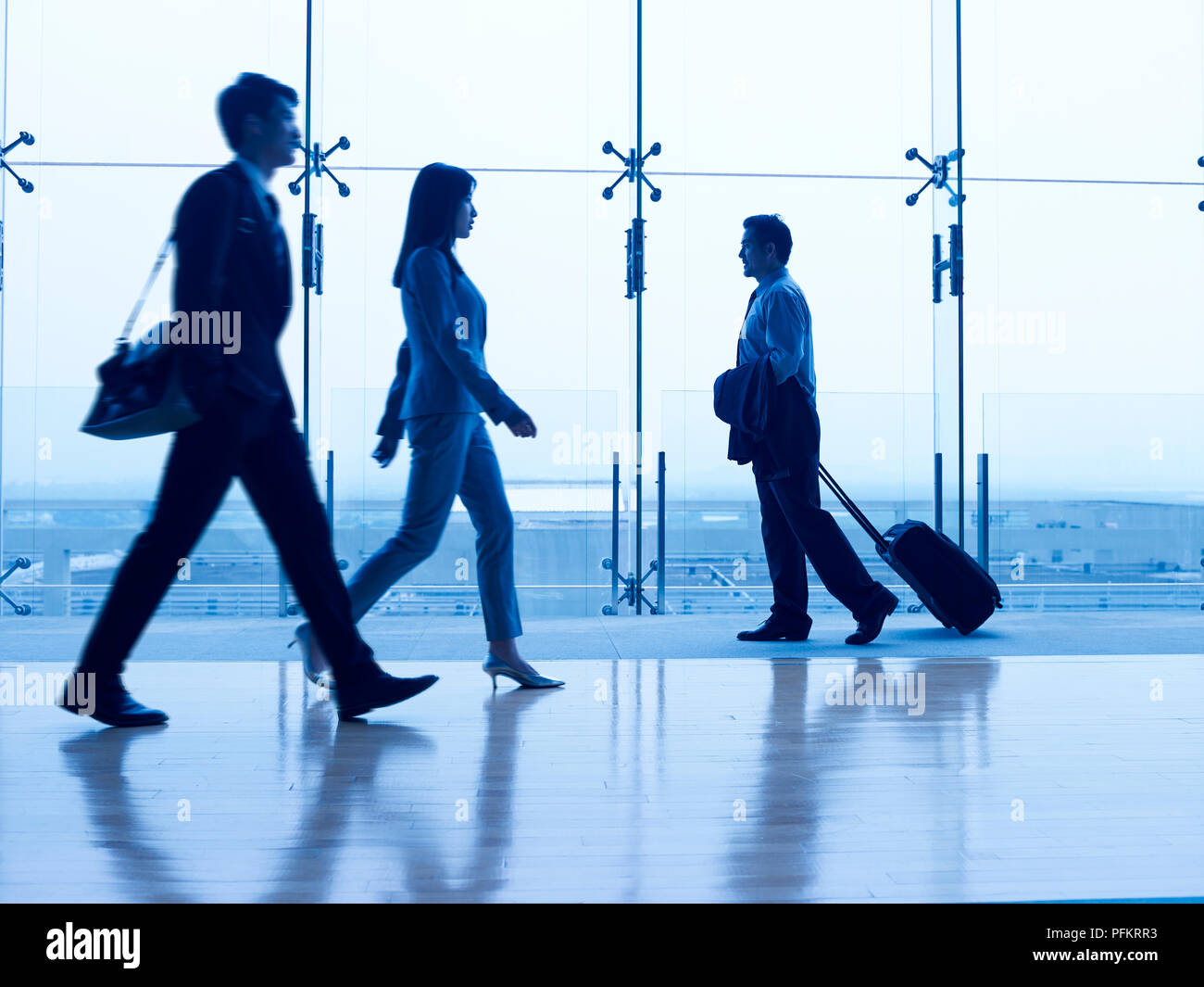 Asian business persone che camminano in airport terminal, concentrarsi sullo sfondo. Foto Stock