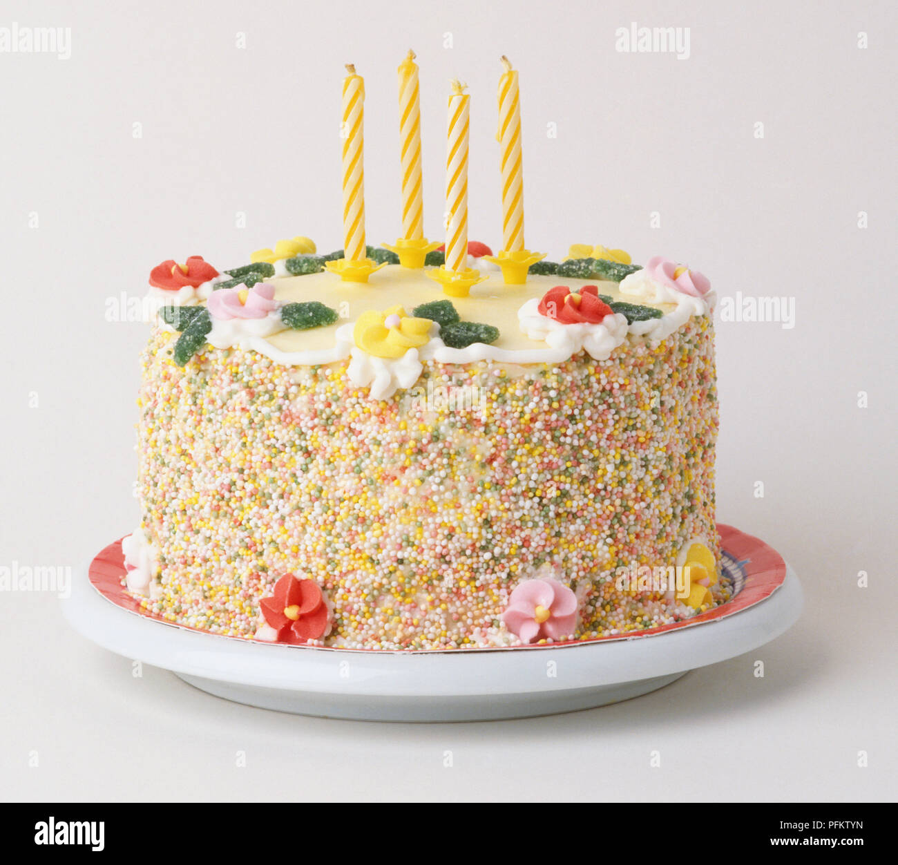 Torta di compleanno decorata con fiori di caramelle, quattro candele e un  confine di multi-colore spruzza Foto stock - Alamy