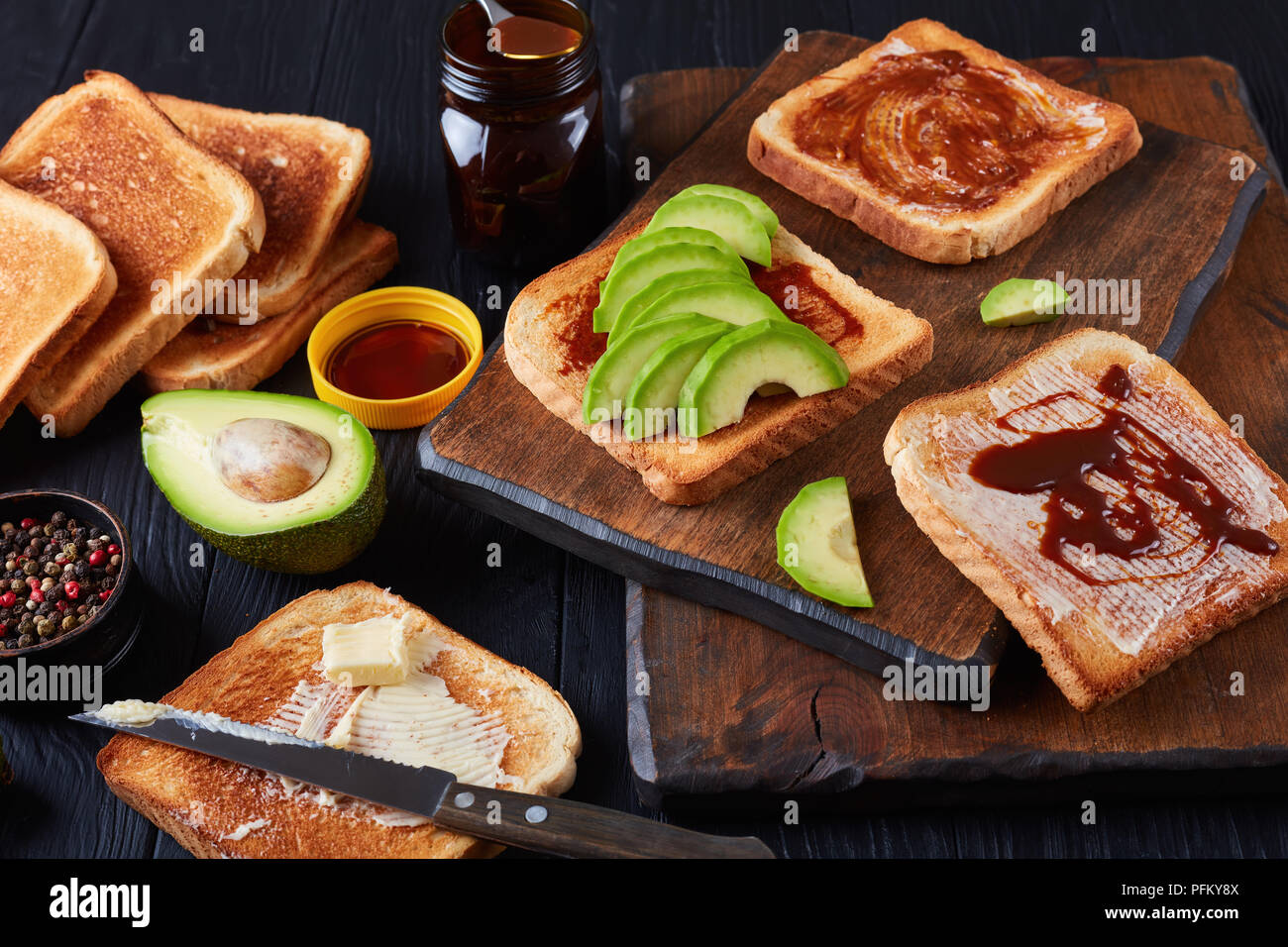 Spicy fette biscottate con burro, fette di avocado e cibo sano diffusione realizzato da avanzi di estratto di lievito di birra con spezie e verdure, vista da sopra, Foto Stock