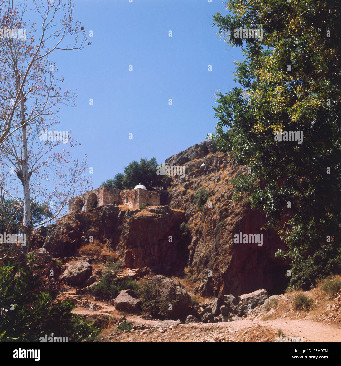 Banias, conosciuto anche con il nome romano di Cesarea di Filippo, tetto bianco chiaramente visibile contro rockface, vicino castello Nimrod, Cisgiordania, Israele. Foto Stock