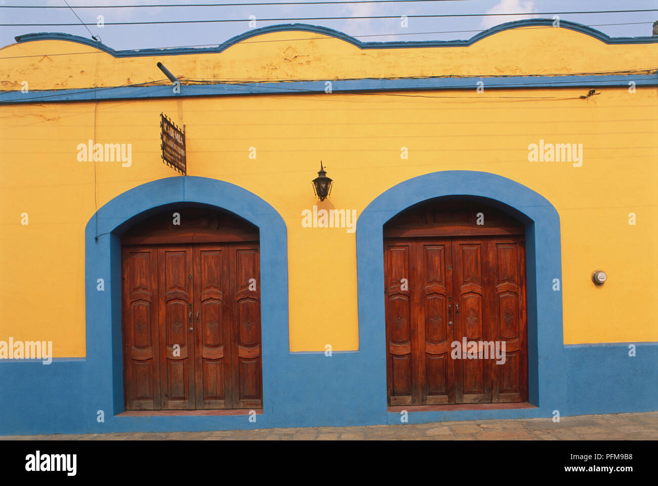 Messico, San Cristobal de las Casas, arancio e blu facciata di un inizio di casa coloniale con pesanti porte di legno e un tetto piatto. Foto Stock