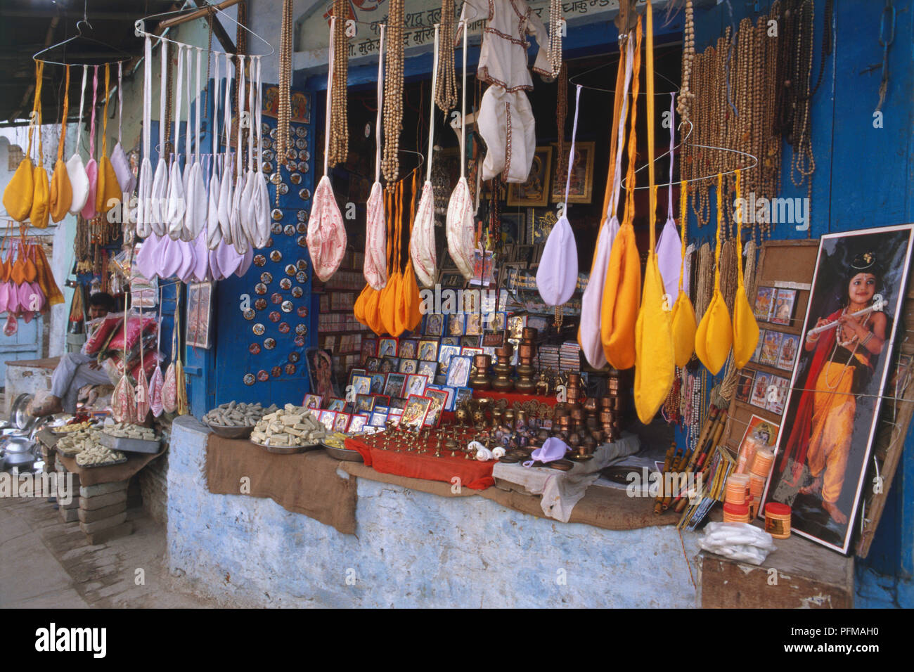 India, Govardhan, città del pellegrino, bancarella vendendo vivacemente colorati oggetti di stoffa, perline, ornamenti e quadri religiosi. Foto Stock