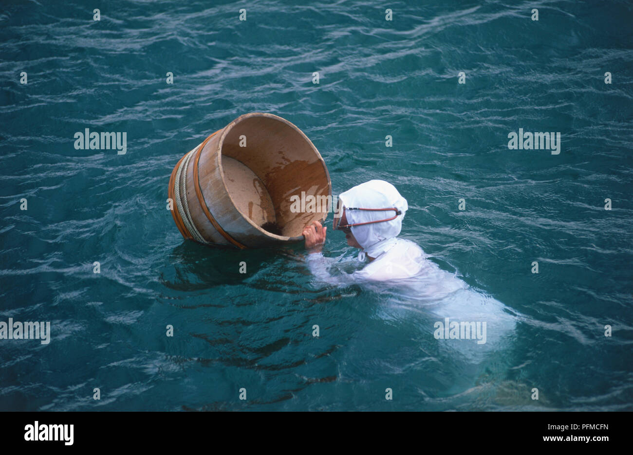Giappone, Honshu, penisola di ghiaccio, donna subacqueo la raccolta di alghe e ricci di mare in un recipiente di legno nel mare di Mikimoto Pearl Island Foto Stock