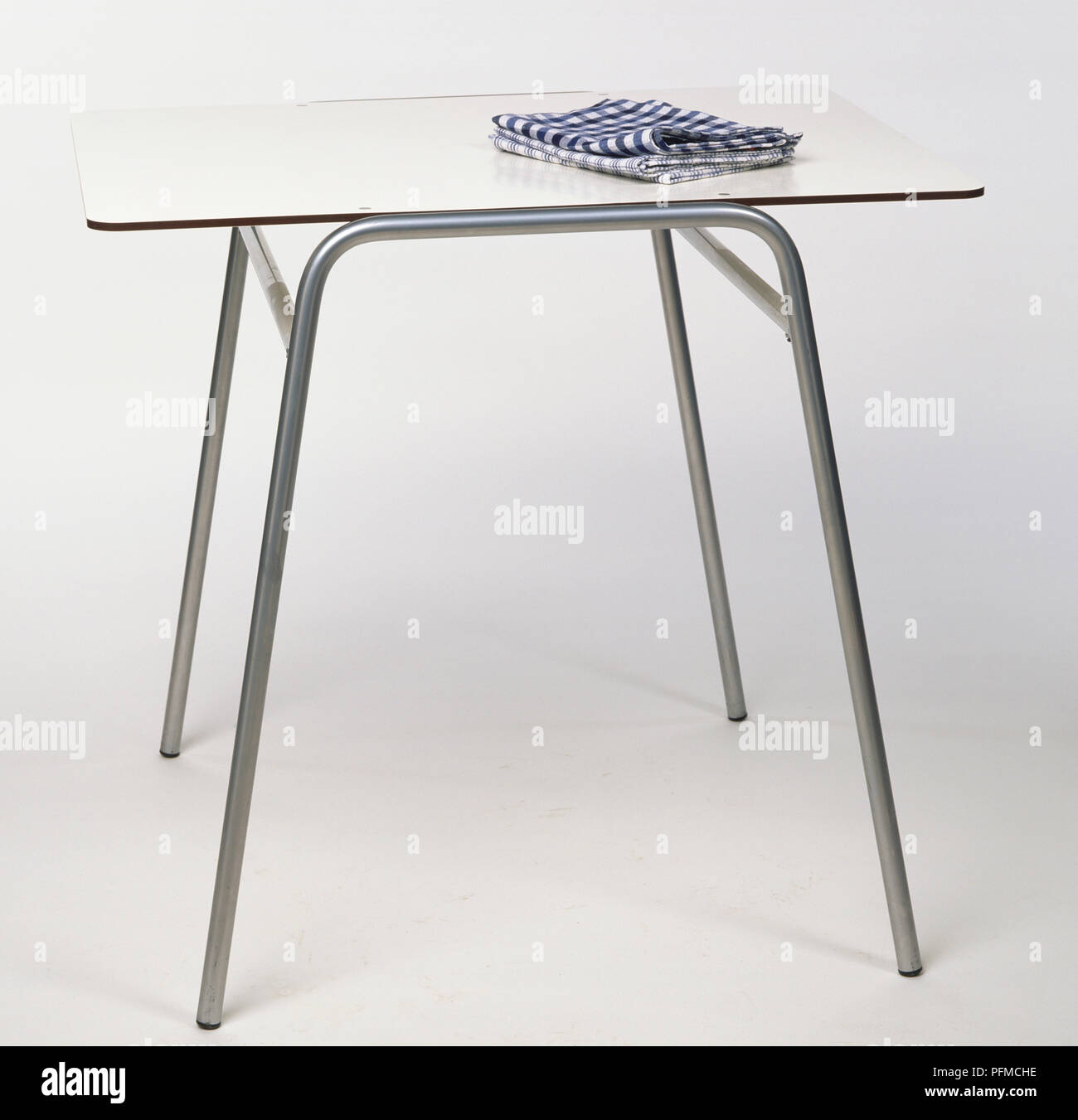 Un stile anni cinquanta, compensato e tavolo in metallo, piegato tovagliolo collocato su un tavolo. Foto Stock